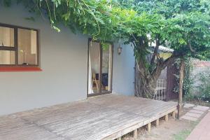a wooden bench next to a house with a tree at Plumb cottage, Greenside in Johannesburg