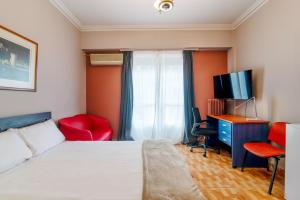 um quarto com uma cama, uma secretária e uma televisão em Charlie city center room em Atenas