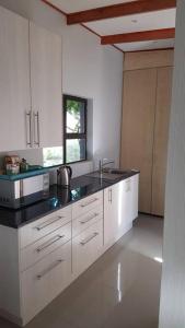 a kitchen with white cabinets and a sink at Plumb cottage, Greenside in Johannesburg