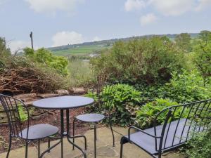 a patio with two tables and chairs and a view at The Other Place in Holmfirth