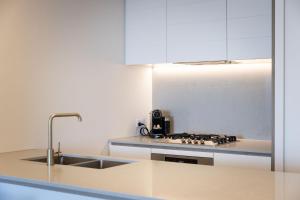 a white kitchen with a sink and a stove at ULTIQA Signature at Broadbeach in Gold Coast