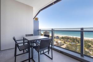 a table and chairs on a balcony with a view of the ocean at ULTIQA Signature at Broadbeach in Gold Coast