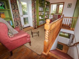 a living room with a staircase and a red chair at The Other Place in Holmfirth