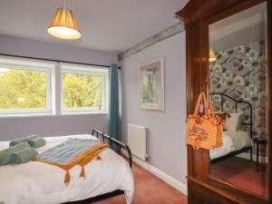 a bedroom with a bed and two windows at The Other Place in Holmfirth