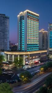 un gran edificio con coches estacionados en un estacionamiento en Kingdom Hotel, en Yiwu