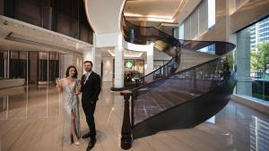 a bride and groom standing next to a staircase in a building at Kingdom Hotel in Yiwu