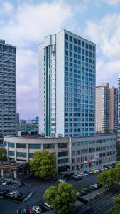 een groot gebouw met auto's geparkeerd op een parkeerplaats bij Kingdom Hotel in Yiwu