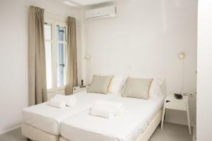 a white bedroom with a large white bed with white pillows at Seaside Paros Ampelas in Ambelas