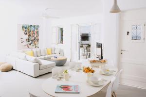 a white living room with a table and a couch at Seaside Paros Ampelas in Ambelas
