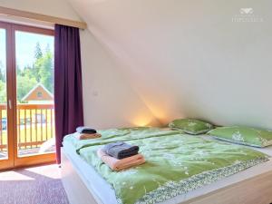 Una cama con sábanas y almohadas verdes en una habitación con balcón. en Apartment HORTENZIJA near Terme Topolšica, en Topolšica