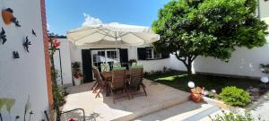 a table and chairs under an umbrella in a yard at Flowers & Faces Guesthouse in Ponte de Lima