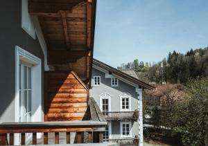 a white house with a wooden porch and a balcony at HENRI Country House Kitzbühel in Kitzbühel