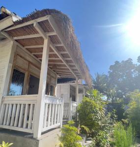 a white house with a porch and a balcony at The Layar Homestay in Nusa Penida