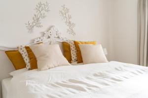 ein weißes Bett mit gelben und grauen Kissen in der Unterkunft Ferienwohnung Gartenkamp Celle in Celle