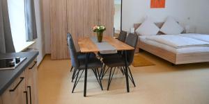 a dining room table with black chairs and a bed at Ferienappartements inTOuR in Ockfen
