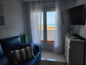 Una sala de estar con un sofá azul y una ventana grande. en El apartamento de Lola, en Mogro