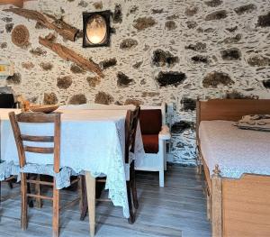 Habitación con mesa, sillas y pared de piedra. en Casa Pappadiana Traditional stonehouse, en Kefálion