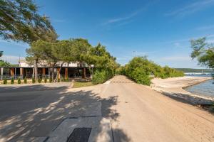 an empty road next to a beach with trees at Guest House Malenica in Sukošan