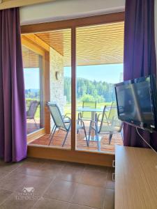 - un salon avec une télévision et une terrasse couverte dans l'établissement Apartment HORTENZIJA near Terme Topolšica, à Topolšica