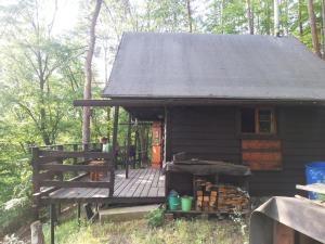 a small cabin with a deck in the woods at Chatrč pod Babou in Křivoklát