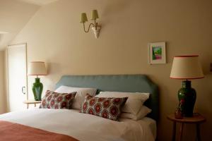 una camera da letto con un letto con cuscini e due lampade di The Queen's Head a Broad Chalke