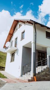 een wit huis met een balkon en een trap bij Casa de vacanta Naty in Bistriţa