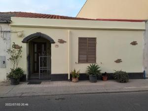 una casa bianca con una porta e piante in vaso di Casa vacanze Antonella a Oristano