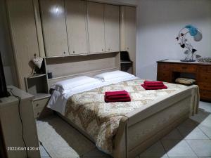 Casa vacanze Antonella في أوريستانو: غرفة نوم بها سرير ووسادتين حمرا