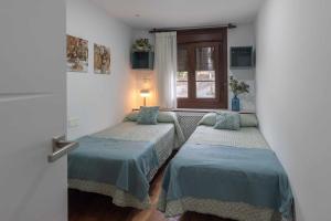 2 camas individuales en una habitación con ventana en Apartamentos La Corrada de Andrín en Andrín