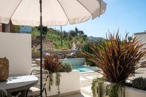 a patio with a table and an umbrella and plants at Casa da Aguda in Colares