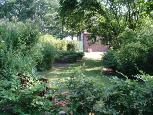 a garden with bushes and trees and a building at De Erfdijk in Herpen