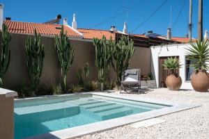 a swimming pool in front of a house with cactus at Casa da Ursa in Colares