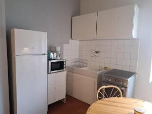 una pequeña cocina con nevera blanca y mesa en Cosy appartement centre ville 2 chambres, en Vias