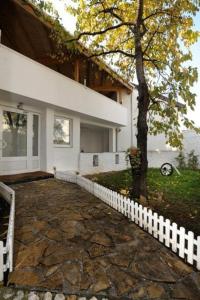 a house with a white fence next to a tree at Hostel Hayat in Sarajevo