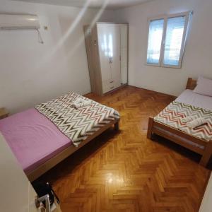Duas camas num quarto com pisos em madeira em Real Apartments em Budva