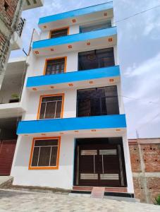 a white and blue building with orange accents at OYO HOME Satvik Homestay in Ayodhya