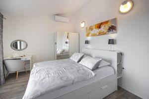 a white bedroom with a bed and a mirror at Apartments Villa Luce in Makarska