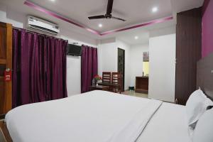 a bedroom with a white bed and purple curtains at OYO Flagship Jazeera Resort in Haddo