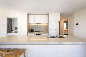 a kitchen with a sink and a white refrigerator at ULTIQA Signature at Broadbeach in Gold Coast