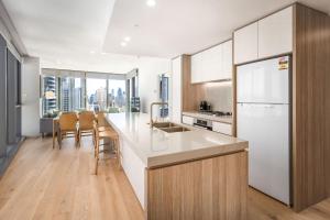 a kitchen with a white refrigerator and a table at ULTIQA Signature at Broadbeach in Gold Coast