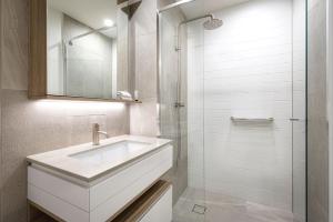 a white bathroom with a sink and a shower at ULTIQA Signature at Broadbeach in Gold Coast