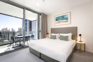a bedroom with a bed and a balcony with a table at ULTIQA Signature at Broadbeach in Gold Coast