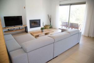sala de estar con sofá blanco y TV en Modern Villa in Cala Jondal Porroig, en Sant Josep de sa Talaia