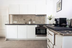 a kitchen with white cabinets and a black counter top at Haus Roserlheim in Pörtschach am Wörthersee