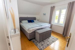 a small bedroom with a bed and a ottoman at Haus Roserlheim in Pörtschach am Wörthersee