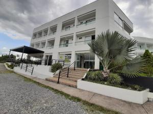 a white building with a palm tree in front of it at Hotel Palmeras De Luz in Moniquirá