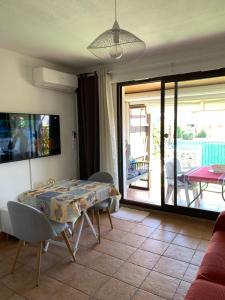 a living room with a table and chairs and a patio at Appartement rue de l'amarrage à PORT GRIMAUD avec Terrasse vue canaux et garage in Grimaud