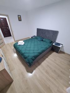 - une chambre avec un lit et une couette verte dans l'établissement Garsoniera Luxury Lorena, à Piteşti