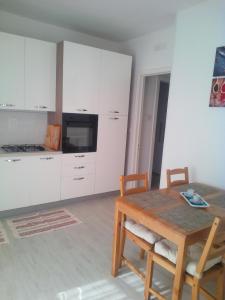 a dining room with a wooden table and white cabinets at CASA VACANZA YDROUS in Otranto +9 photos
