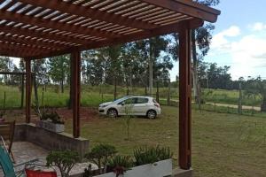 a white car parked under a wooden pergola at El Paraíso - Casa rural en zona termal de Concordia in Concordia